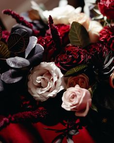 a bunch of flowers that are on top of a red table cloth and some leaves