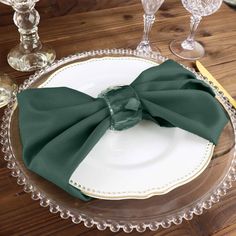 there is a plate with a green bow on it and two wine glasses next to it