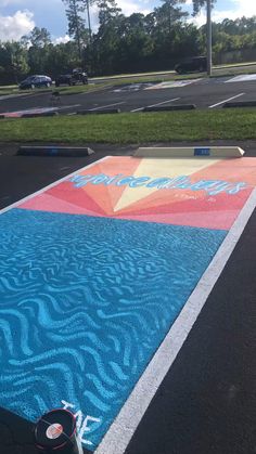 an empty parking lot with blue and pink painted on it, next to a skateboard ramp