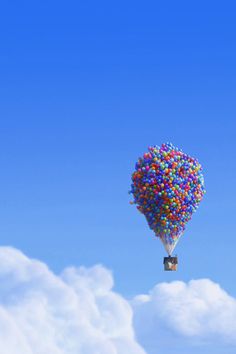 a hot air balloon floating in the sky with lots of colored balls attached to it