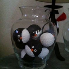 four penguins in a glass vase sitting on a table