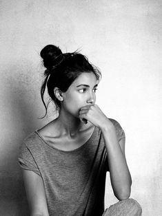 black and white photograph of a woman sitting on the floor with her finger in her mouth