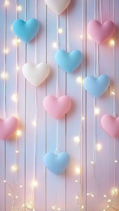 several heart shaped balloons hanging from strings on a wooden wall with lights in the background