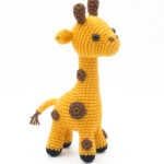 a knitted giraffe toy sitting on top of a white surface