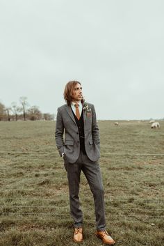 a man standing in a field wearing a suit and tie