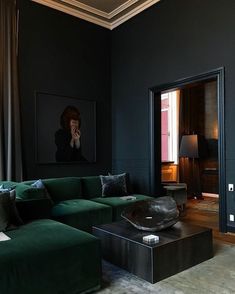 a living room with black walls and green couches