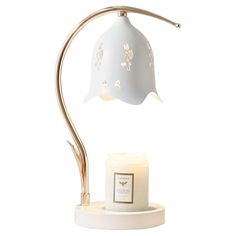 a table lamp with a candle in front of it on a white base and gold accents