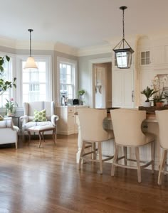 a living room filled with furniture next to a kitchen and dining room table covered in white chairs