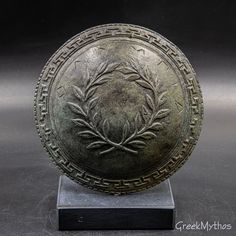 a bronze plate with an image of a plant in the center on a black base