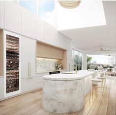 a kitchen with white cabinets and marble counter tops next to a large wine rack on the wall