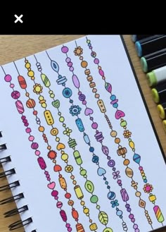 an open notebook with colorful doodles on the page and colored pencils next to it