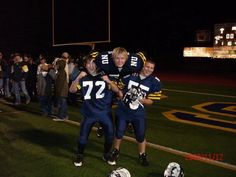 two football players hugging each other in front of a crowd on a field at night