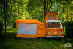 an orange and white camper van parked in the grass with it's door open