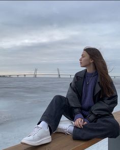 a woman sitting on a bench looking out over the water