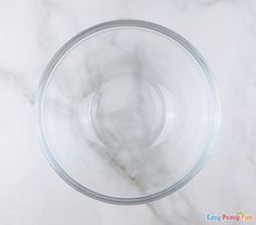 a glass bowl sitting on top of a white marble counter next to an empty cup