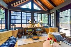 a living room filled with lots of furniture and large windows covered in wood shinning