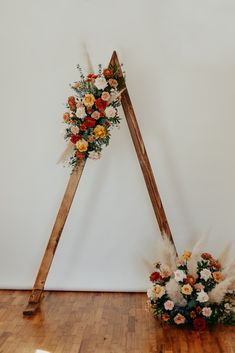 an arrangement of flowers is placed on the floor in front of a large white wall