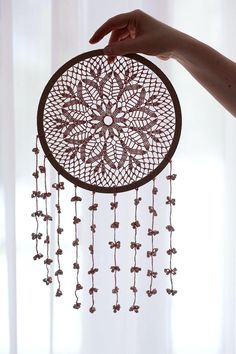 a person holding up a decorative item with beads hanging from it's centerpiece