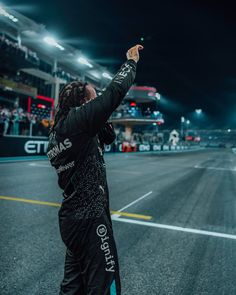 a person standing on the side of a race track taking a photo with their cell phone