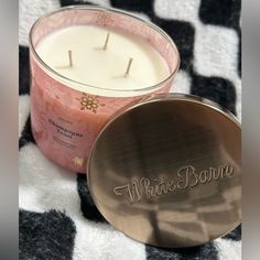 a pink candle sitting on top of a black and white checkered blanket next to a metal container