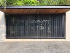 an open garage door in front of a white wall with trees on the other side