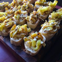 several pieces of bread with cheese and other toppings on it sitting on a cutting board