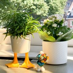 two potted plants sitting on top of a window sill next to a rubber duck