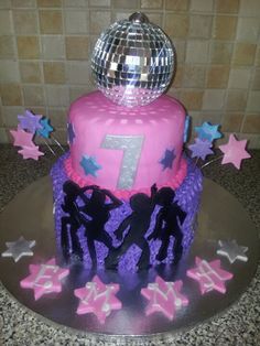 a pink cake with purple icing and stars around it on a silver platter