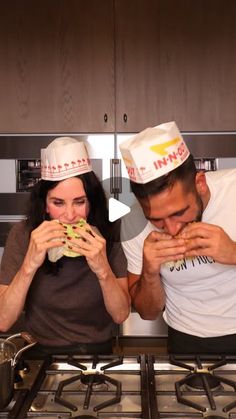 a man and woman in chef hats are eating sandwiches