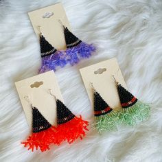 three pairs of earrings with tassels on them sitting on a white fur surface