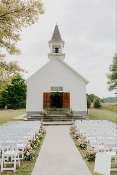 an outdoor ceremony with white chairs and flowers