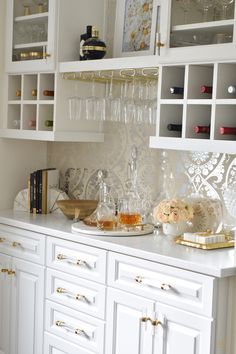 a kitchen with white cabinets and glassware on the counter top in front of it