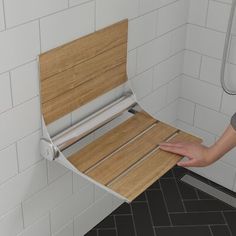 a person with their hand on the back of a wooden bench in a shower stall