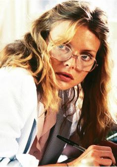 a woman sitting at a desk with a pen and paper in front of her face