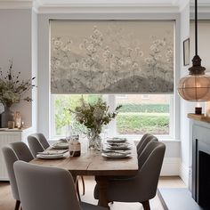 a dining room table set with place settings and flowers in vases on the side