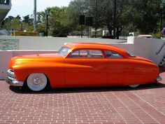 an orange classic car parked in front of a building