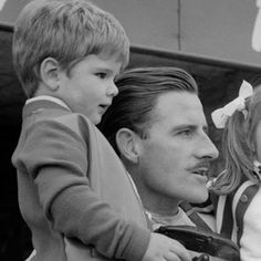 a black and white photo of a man holding a little boy in his lap,