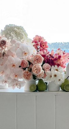 flowers in white vases sitting on a window sill