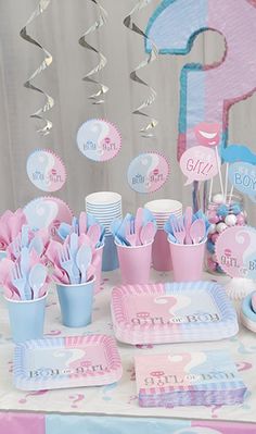 a pink and blue gender reveal party set up with plates, cups, napkins and decorations