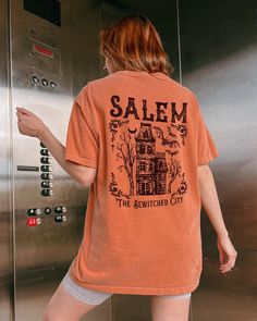 Comfort Colors® Salem Massachusetts shirt, Salem Witchy Haunted House shirt for her, Witch Tshirt, Halloween Party T-shirt Vintage Fall Tee These are Unisex Garment-Dyed T-shirt made 100% with ring-spun cotton. Shirts look retro and vintage. The soft-washed, garment-dyed fabric brings extra coziness to your wardrobe while the relaxed fit makes it an excellent daily choice. FEATURES - Medium fabric (6.1 oz/yd² (206.8 g/m - Relaxed fit - Sewn-in twill label - 100% ring-spun cotton - Without side seams - Garment-dyed fabric - Double needle stitching on all seams Sizing * Please refer to the size chart in the listing photographs to determine your size. * If you are not sure what size to order, you can measure a shirt you already own to see what size would fit you best. Our shirts are measured Spooky Orange Crew Neck Top, Spooky Relaxed Fit Screen Print T-shirt, Spooky Screen Print Relaxed Fit T-shirt, Halloween Relaxed Fit Crew Neck Shirt, Spooky Short Sleeve Orange Shirt, Halloween Graphic Print Short Sleeve Top, Halloween Screen Print Relaxed Fit Shirt, Spooky Short Sleeve Shirt With Letter Print, Spooky Short Sleeve Top With Graphic Print