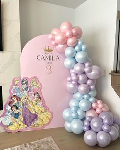 a balloon arch with princesses on it next to a pink sign that says camila