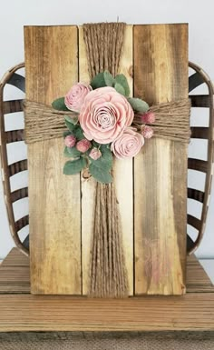 a wooden chair with pink flowers on the back and green leaves attached to it's sides