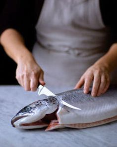 a person cutting up a fish with a knife