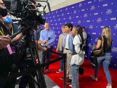 a group of people standing on top of a red carpet next to a blue wall