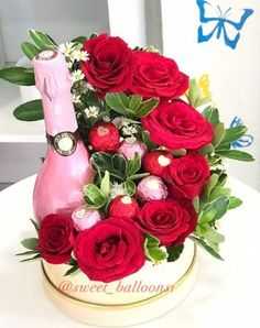 a bouquet of red roses in a hat box with a bottle of champagne on top