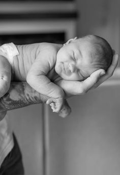 a black and white photo of a baby being held by a person's hand