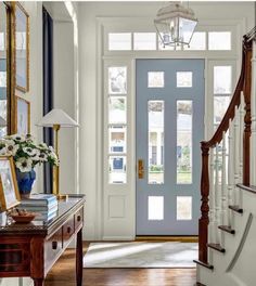 a blue front door with two framed pictures on the wall and a white staircase leading to it