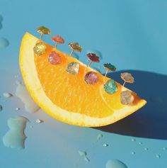 an orange cut in half with gems on it's side and water droplets surrounding it