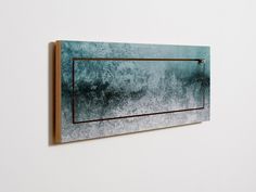 a painting hanging on the wall next to a white wall with a wooden frame and metal bar