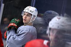 a hockey player is standing in front of the net with his hands on his shoulder